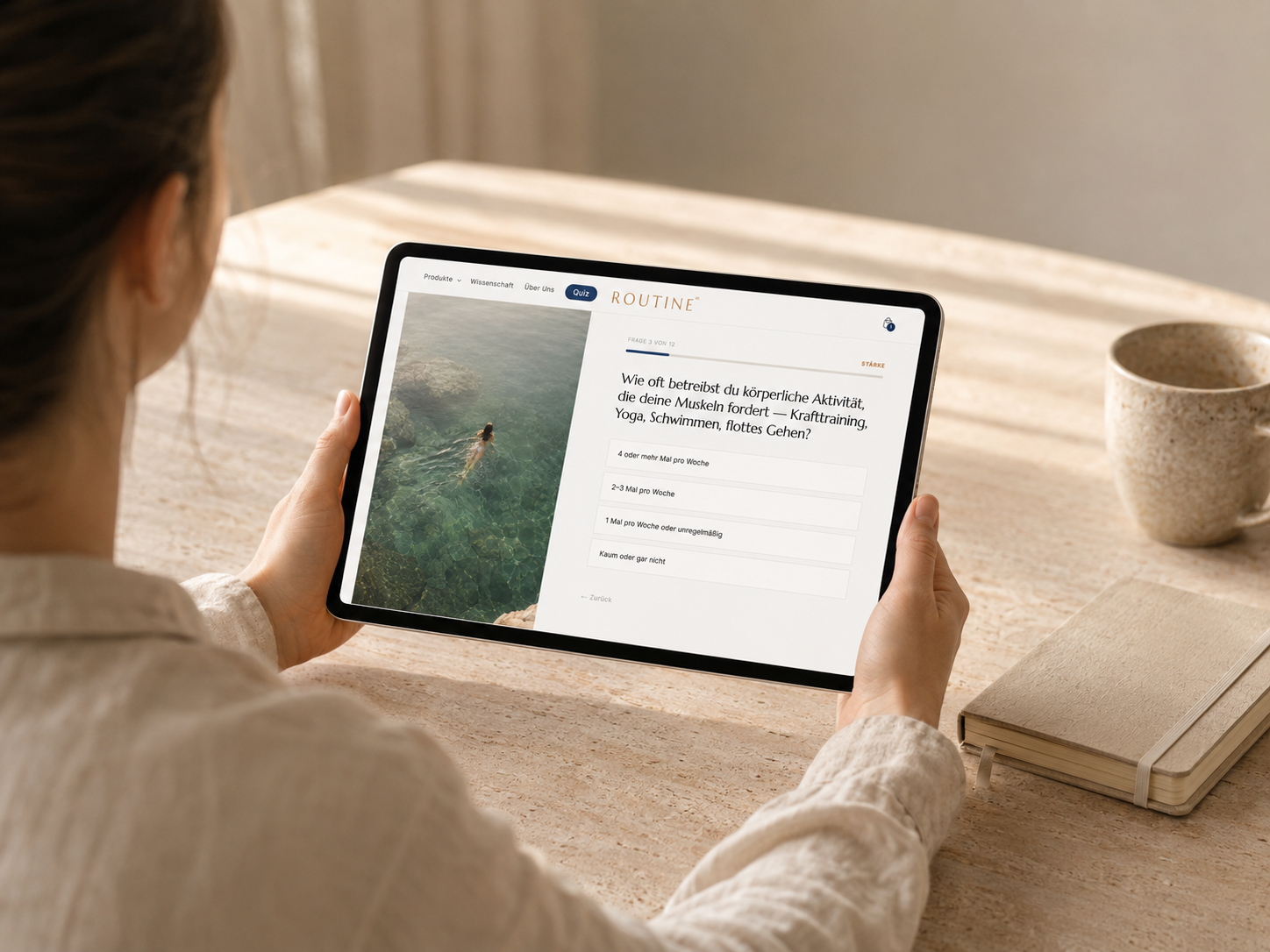 Person hält iPad mit Gesundheits-Quiz auf hellem Travertin-Schreibtisch im warmen Morgenlicht – minimalistisches Wellness- und Longevity-Setting mit Keramiktasse und Notizbuch.