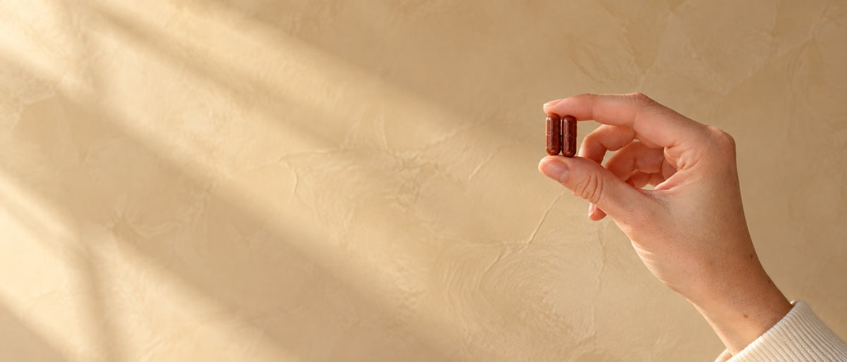 ROUTINE8 Zellschutz Komplex Nahrungsergänzungsmittel mit Astaxanthin, zwei tiefrote Kapseln vor heller Wand.